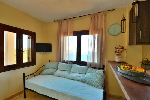 a living room with a blue couch and a window at Kalithea Studio Aptera in Megála Khoráfia