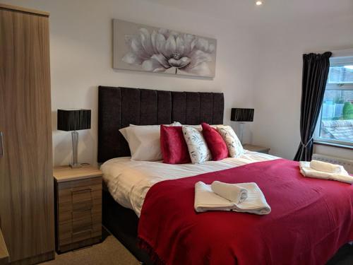 a bedroom with a large bed with a red blanket at Avon House in Telford