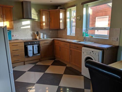 a kitchen with wooden cabinets and a checkered floor at Avon House in Telford