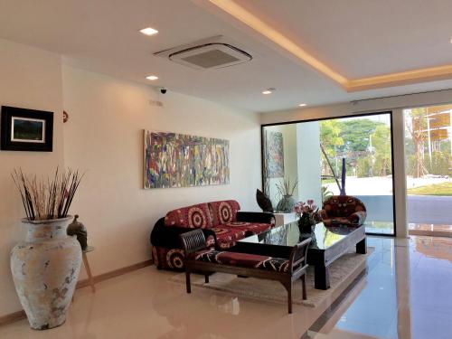 a living room with a couch and a table and a vase at Porestva Hotel Sriracha in Si Racha