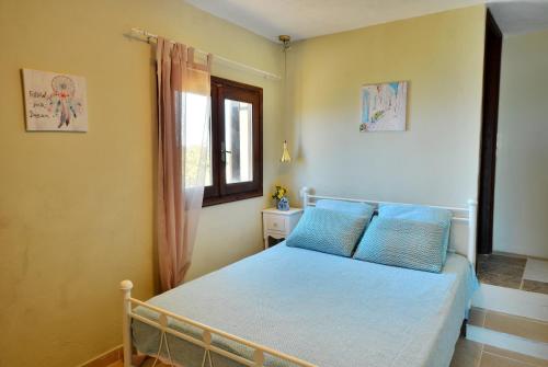 um quarto com uma cama com almofadas azuis e uma janela em Kalithea Studio Aptera em Megála Khoráfia