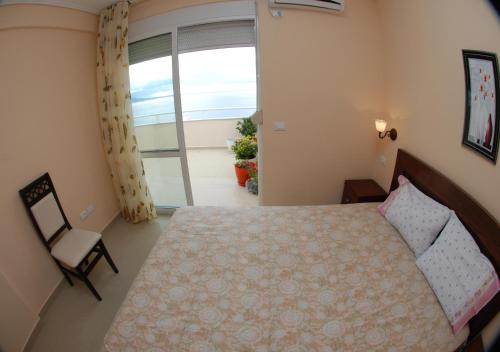 um quarto com uma cama, uma cadeira e uma janela em Erti's Apartments em Saranda