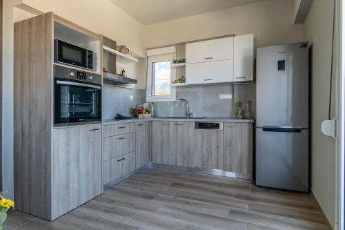 a kitchen with wooden cabinets and a refrigerator at Kyma seaview Apartments, Episkopi beach Rethymno in Karotí