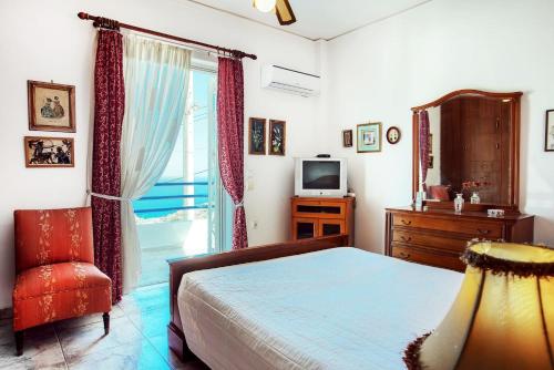 a bedroom with a bed and a television and a chair at A gem next to the sea and close to the airport in Dhaskalión