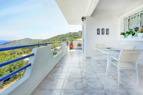 a white house with a balcony with a table and chairs at A gem next to the sea and close to the airport in Dhaskalión