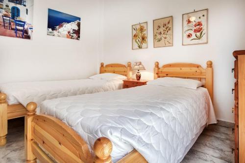 two beds in a room with white sheets at A gem next to the sea and close to the airport in Dhaskalión