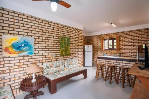 a living room with a brick wall and a kitchen at Pousada Canto das Trilhas in Bombinhas