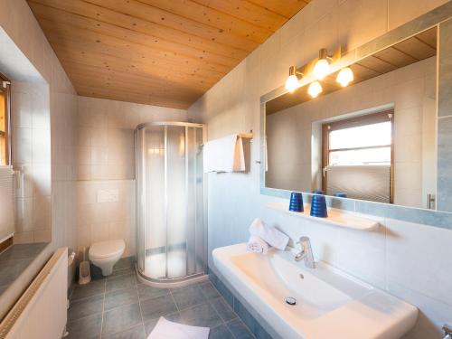 ein Badezimmer mit einer Badewanne, einem Waschbecken und einem Spiegel in der Unterkunft Apartments Quehenberger in Maishofen