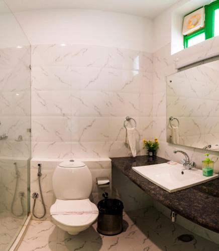 a white bathroom with a toilet and a sink at Coral Country Homestay in Agra