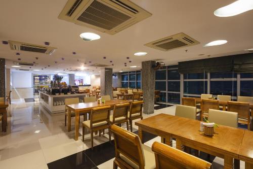 a restaurant with wooden tables and chairs and a kitchen at Prime New Hotel in Nha Trang