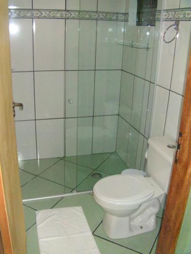 a bathroom with a toilet and a glass shower at Pousada Pinhalense in Santo Antônio do Pinhal