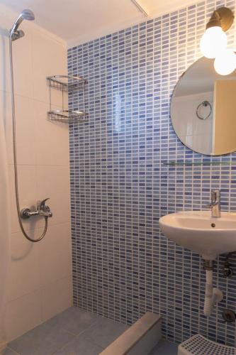 a bathroom with a sink and a shower with blue tiles at Hanioti Home in Hanioti