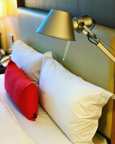a bed with a red and white pillow and a lamp at Ever Delightful Business Hotel in Chiayi City