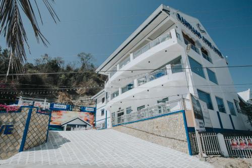 a white building with blue trim next to a street at Santiago Cove Hotel and Restaurant in Santiago