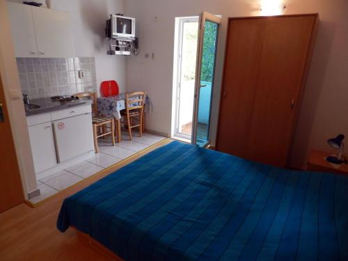 a bedroom with a blue bed and a kitchen at Apartments Senny in Orebić