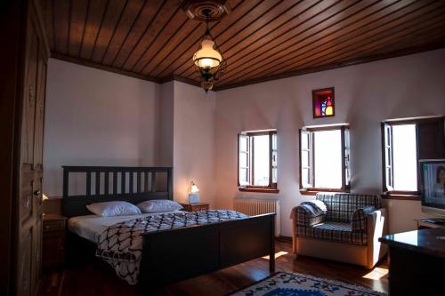sypialnia z łóżkiem, krzesłem i oknami w obiekcie Traditional Mansion Calliopec-UVC sterilized w mieście Makrinítsa