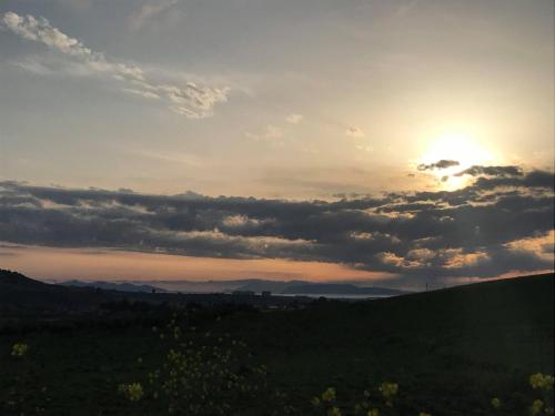 a sunset over a green field with the sun setting at MiraErice in Napola