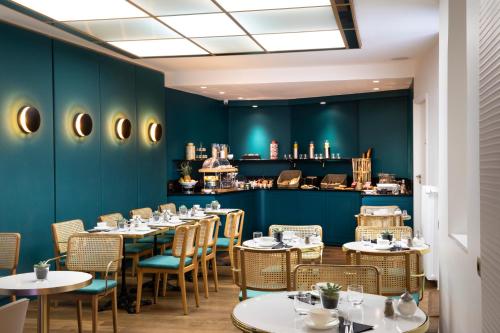 d'une salle à manger avec des tables, des chaises et des murs verts. dans l'établissement Hôtel Victor Hugo Paris Kléber, à Paris