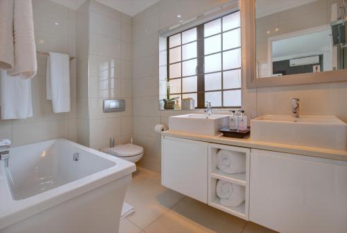 a white bathroom with a tub and a sink and a toilet at African Oceans Manor on the Beach in Mossel Bay