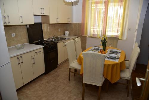 a kitchen with a table with a yellow table cloth at Apartments Maestral in Malinska