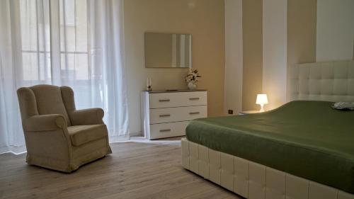 a bedroom with a bed and a chair and a dresser at Palazzo Colombini Apartment in Lucca