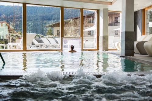 a woman sitting in a swimming pool in a house at Blu Hotel Natura & Spa - Adults Only in Folgaria