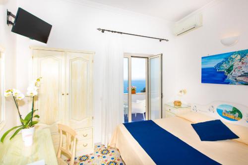 a white and blue bedroom with a bed and a table at Casa Guadagno in Positano