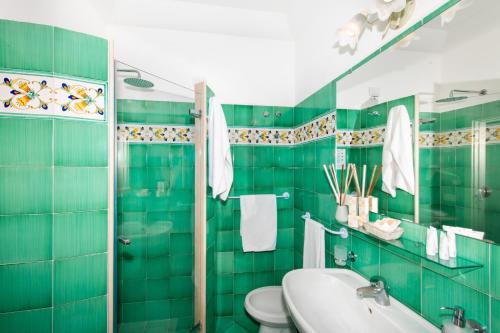 a green tiled bathroom with a toilet and a sink at Casa Guadagno in Positano