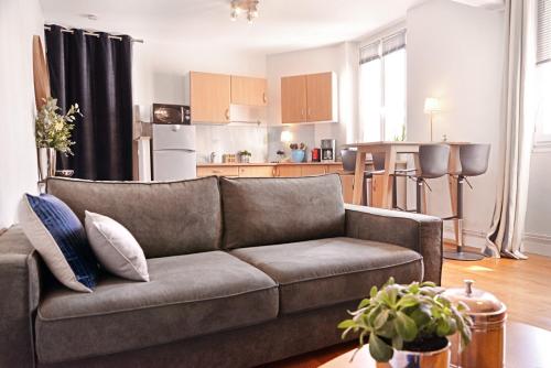 a living room with a couch and a kitchen at Coeur du Boulingrin in Reims