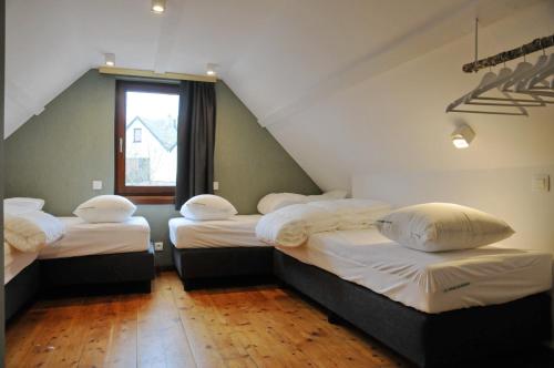 ヴィエルサルムにあるMaison du Lac Vielsalmのベッド3台と窓が備わる屋根裏部屋