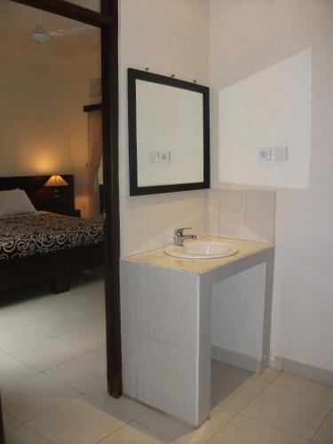 a bathroom with a sink and a mirror and a bed at Gerhana Sari 2 Bungalows in Ubud