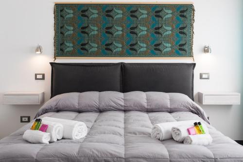 a bed with towels and a painting on the wall at My Way - Suite - Rooms - Palazzo San Matteo in Palermo