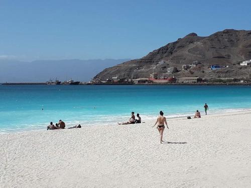 a group of people on a beach near the water at @Georgette in Mindelo