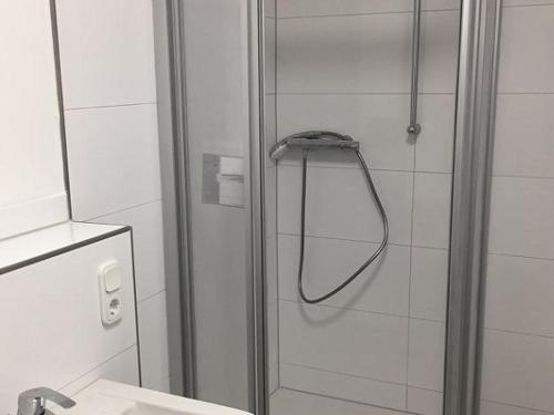 a shower with a glass door next to a sink at City Apartment Dietze in Übach-Palenberg