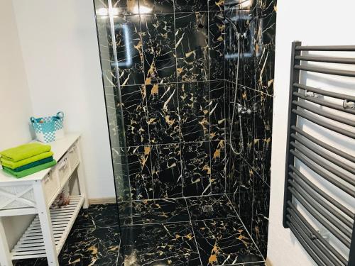 uma casa de banho com um chuveiro com azulejos pretos e dourados em Chata pod Lysou Horou em Ostravice