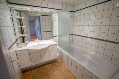 a white bathroom with a sink and a shower at Appt privé / piscine jacuzzi / 10 min à pied de la plage in Pyla-sur-Mer