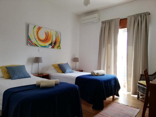 a bedroom with two beds with blue sheets and a window at Guia Guest House in São Bartolomeu de Messines
