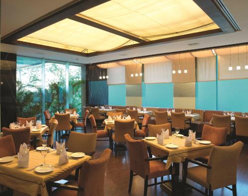 um restaurante com mesas e cadeiras num quarto em Mirage Hotel em Mumbai