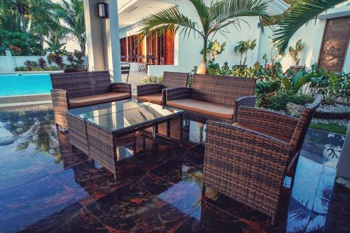 a patio with wicker chairs and a glass table at Quest Villa in Panglao