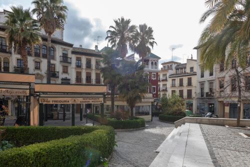 una calle en una ciudad con palmeras y edificios en San Jerónimo 17 Suites en Granada