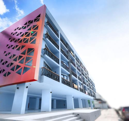 a large white building with a red at Phoenix Hotel Karon Beach in Karon Beach