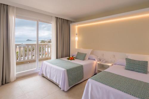 a hotel room with two beds and a balcony at Gran Hotel Peñiscola in Peñíscola