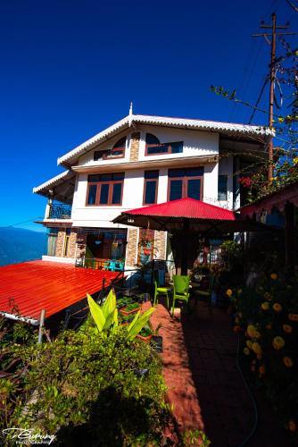 a large building with a red roof and an umbrella at Dreamhome Stay in Kurseong