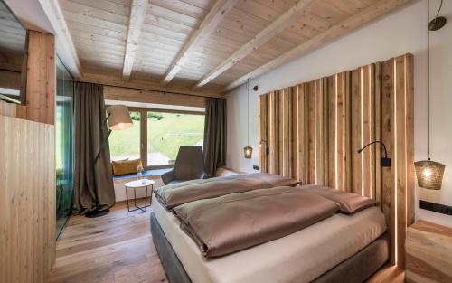 a bedroom with a large bed in a room with wooden ceilings at Hotel Jaufentalerhof in Racines