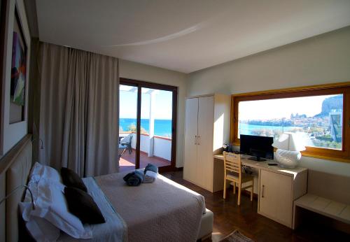 Habitación de hotel con cama, escritorio y ventana en Villa Cerniglia Plus, en Cefalú