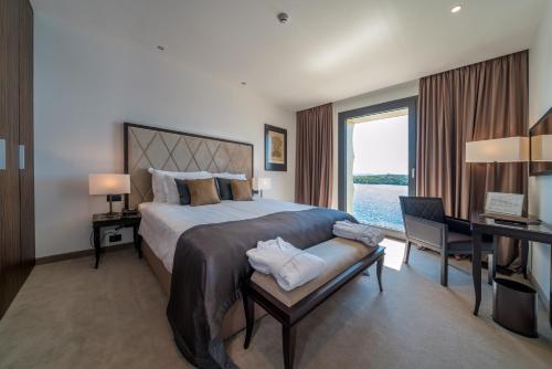 a bedroom with a large bed with a desk and a window at Bellevue Superior City Hotel in Šibenik