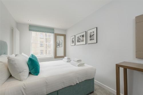 una camera da letto con un grande letto bianco con cuscini blu di Destiny Scotland - Royal Mile Residence a Edimburgo