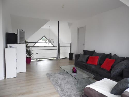 - un salon avec un canapé noir et des oreillers rouges dans l'établissement AU PARFUM DES LAVANDES, à Précigné