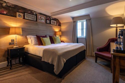 a hotel room with a bed and a chair at The Foley in Claygate