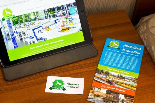 a table with a laptop and two brochures on it at Family Hotel Romantika in Velingrad